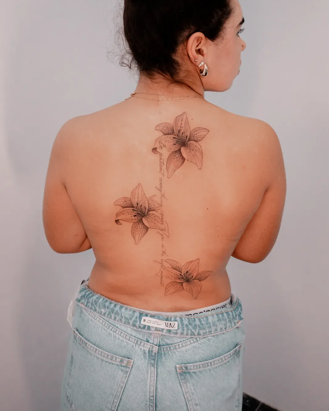 Botanical lilies tattoo along the spine