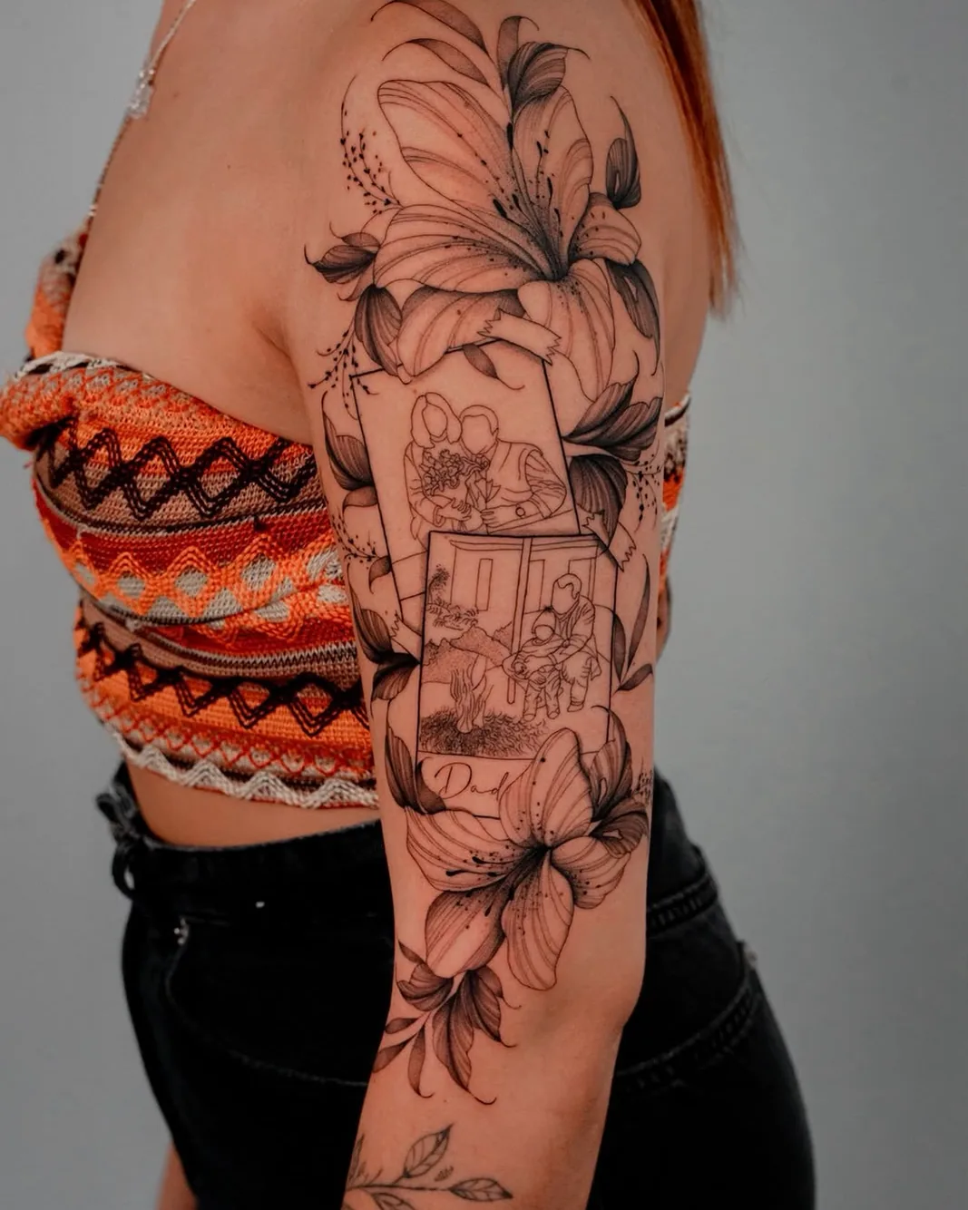 Black and grey lily half-sleeve with family portrait frames, tattooed by Hugo Gonzalez in Funchal, Madeira