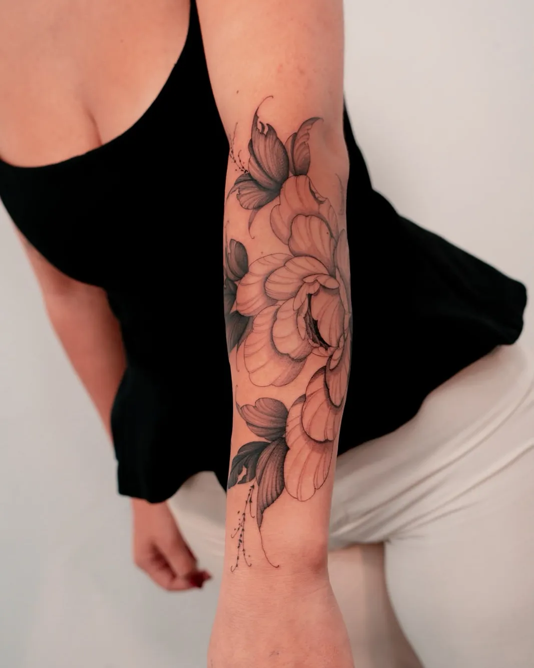 Botanical peony and lily tattoo on the forearm