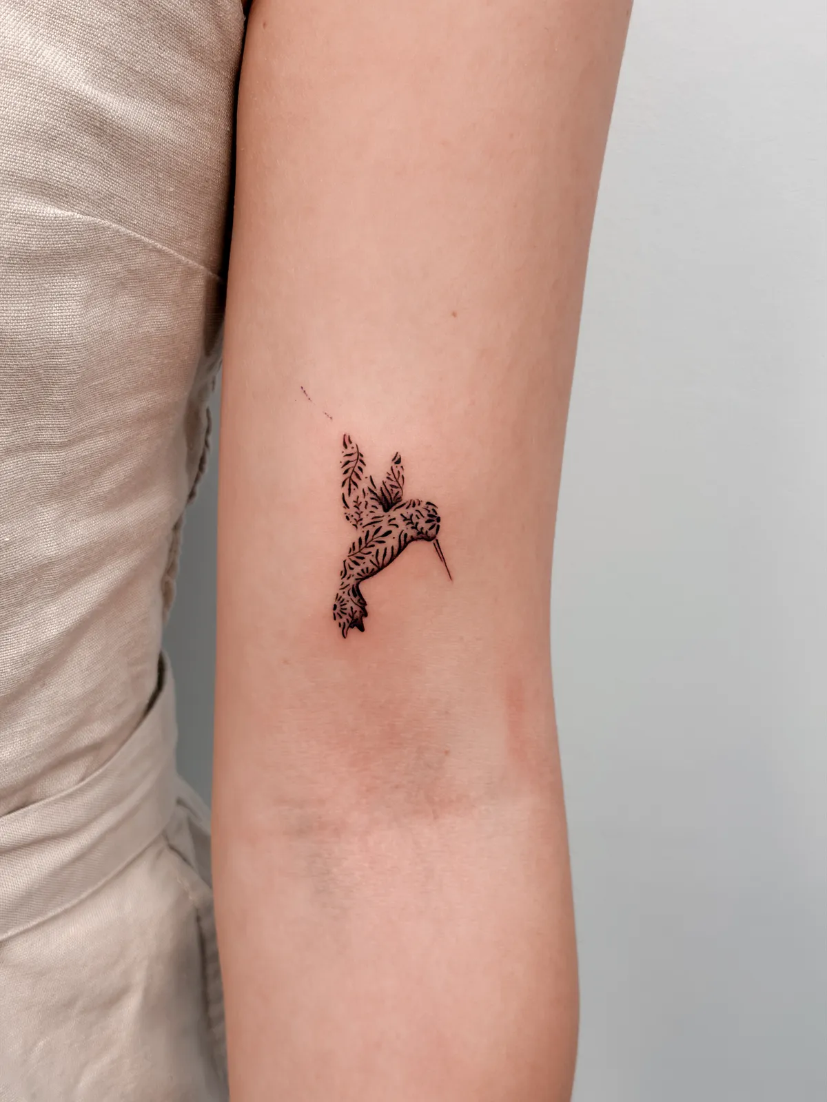 Delicate fine line hummingbird on the arm by Hugo Gonzalez