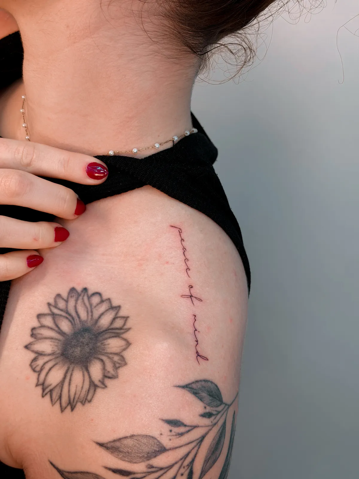 Fine line sunflower on the shoulder with delicate red lettering by Hugo Gonzalez